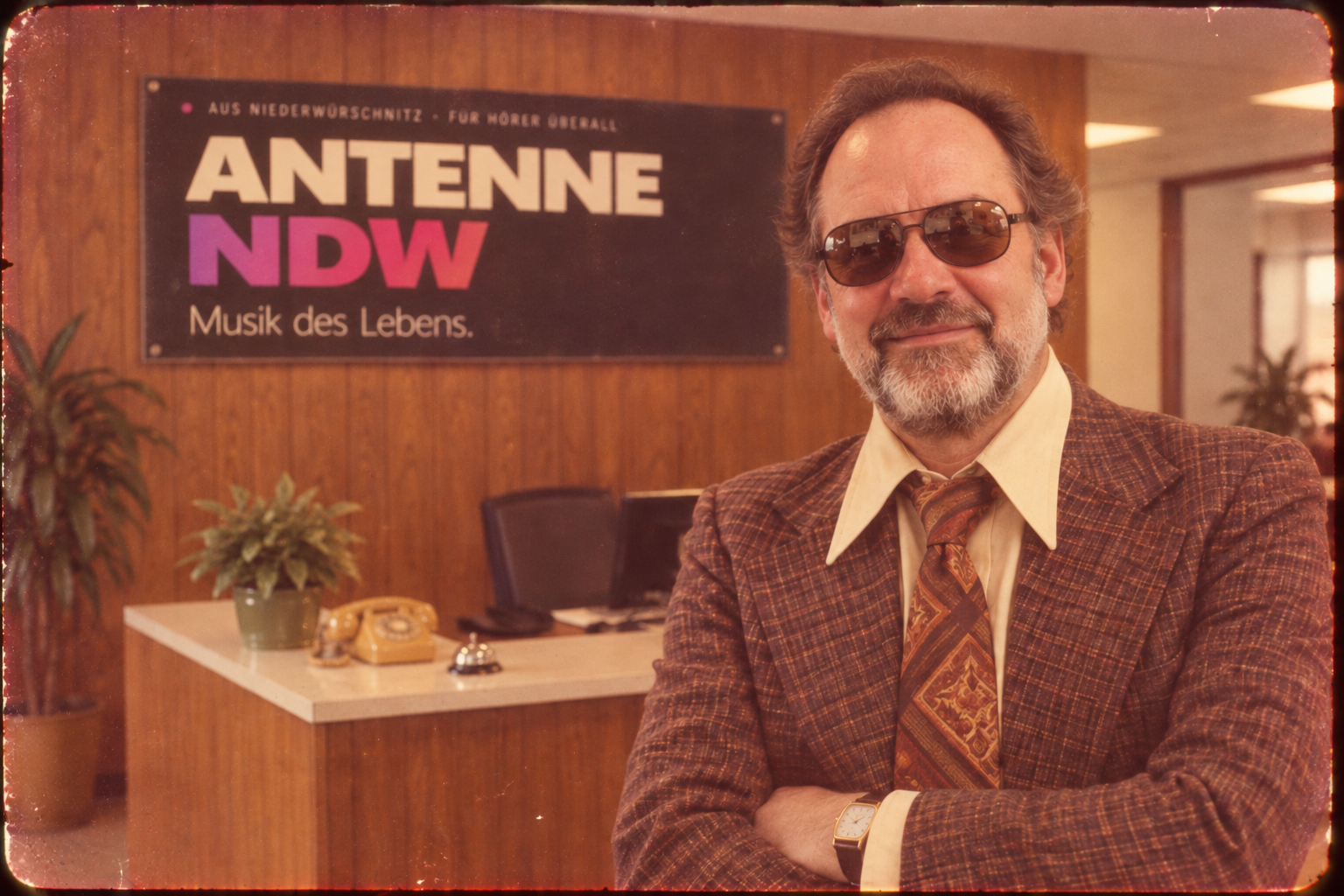 Portr&auml;t im B&uuml;ro vor einem Schild mit der Aufschrift ANTENNE NDW &ndash; Musik des Lebens